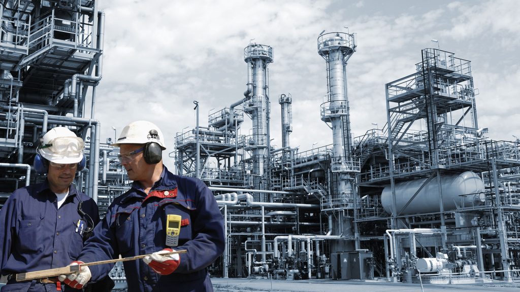 Two engineers in front of large refinery