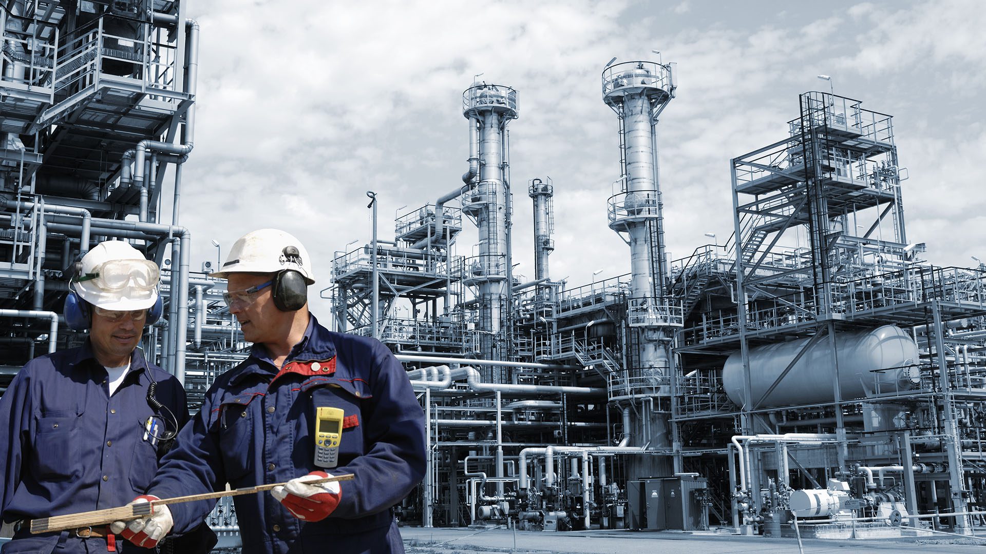 Two engineers in front of large refinery