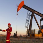 Oil field workers in front of oil derrick